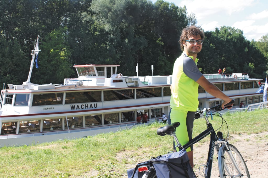 Ciclista accanto a un battello sul fiume Danubio, viaggiare in bici e barca "Girolibero"