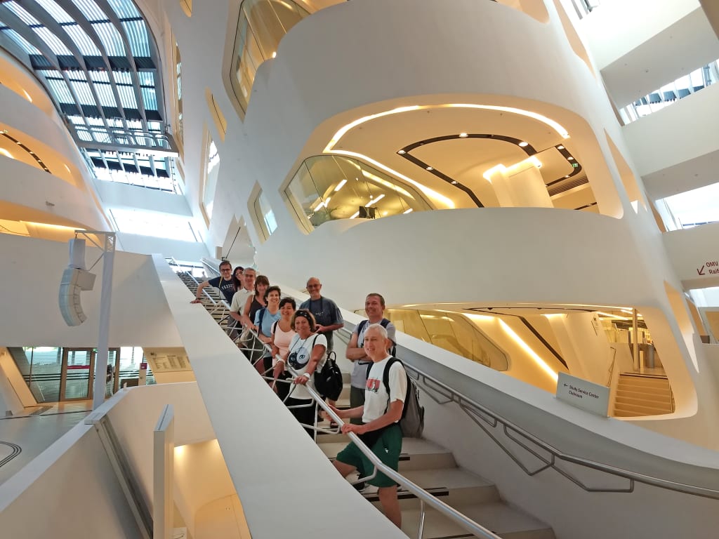 Interno della Facoltà di Economia di Vienna con scala monumentale e visitatori, esempio di architettura contemporanea e cultura urbana