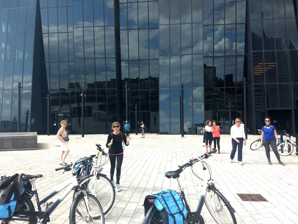 Cicloturisti davanti a edificio moderno nel quartiere Donau City di Vienna, viaggio in bici in città