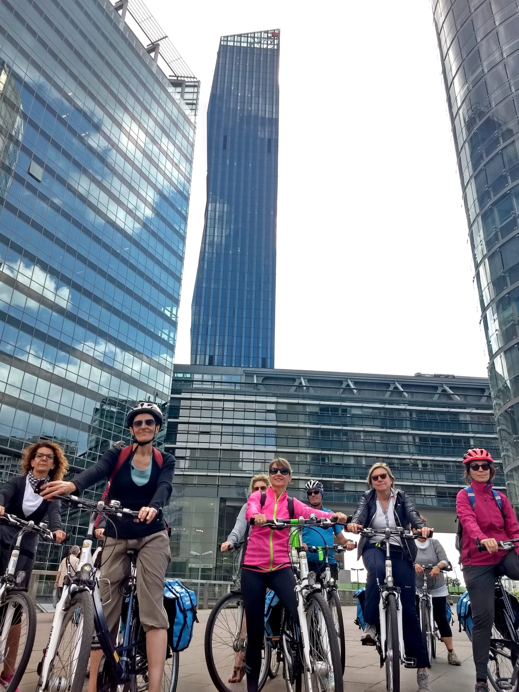 Gruppo di ciclisti davanti a grattacieli di Vienna, viaggio urbano in bici tra architettura e design