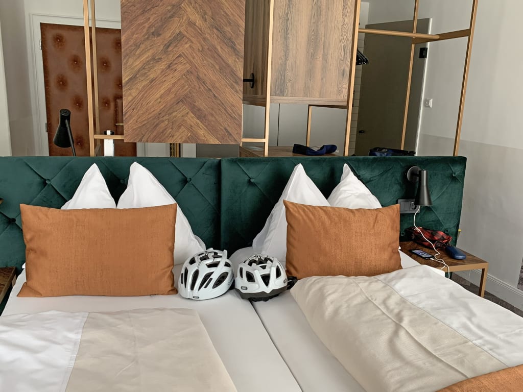 Modernes Zimmer mit Doppelbett und bunten Kissen im Stil eines Boutique-Hotels. Österreich, Alpe-Adria-Radweg