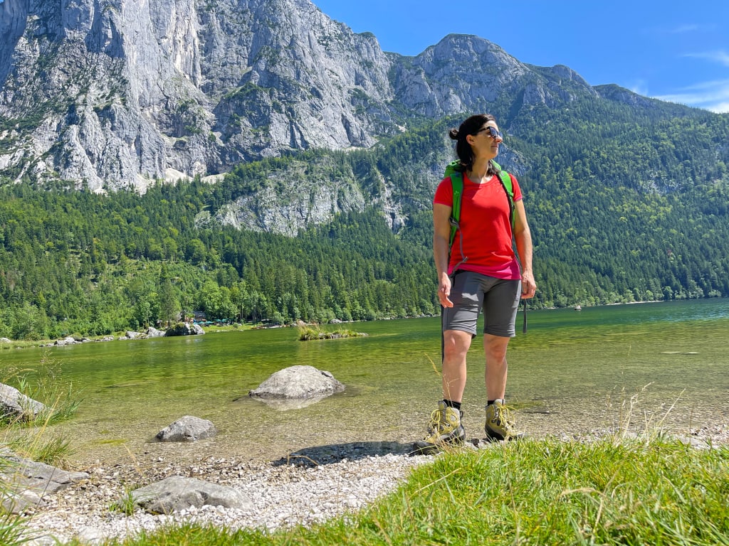 Escursionista vicino a un lago alpino circondato da montagne nel Salzkammergut, vacanze a piedi in Austria "Girolibero"