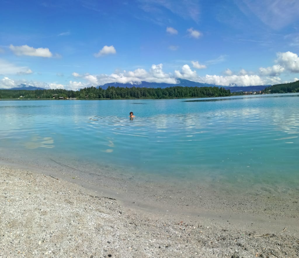 Spiaggia sabbiosa e acqua cristallina di un lago in Carinzia, ideale per le famiglie.
