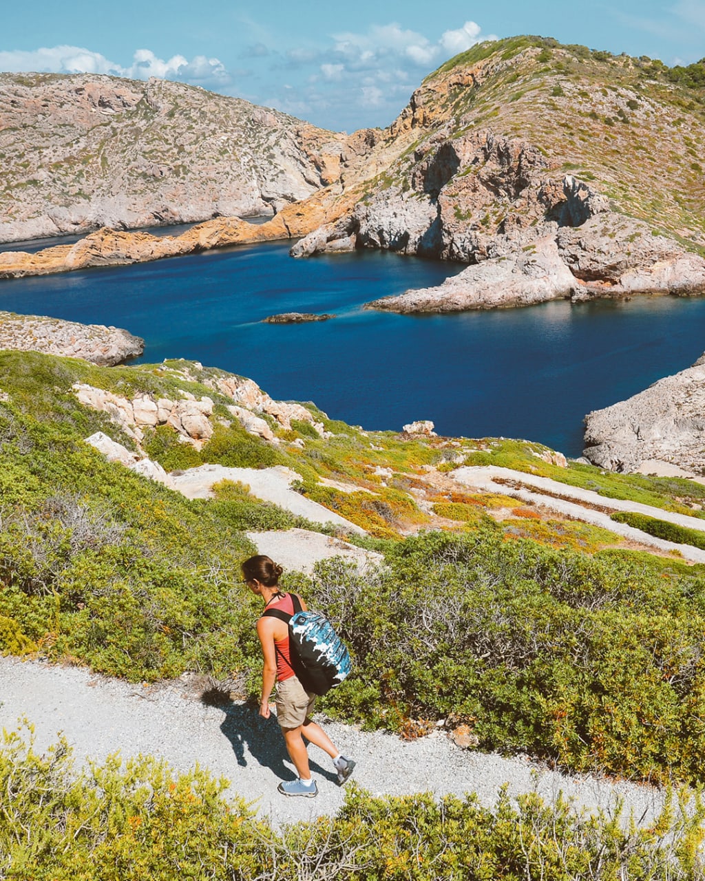 Escursionista che cammina lungo un sentiero costiero, vista su laghi naturali