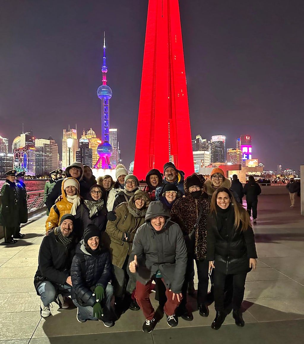 Gruppo di viaggiatori Girolibero davanti a installazione luminosa rossa, Shanghai esperienza urbana notturna