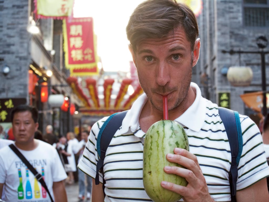 Turista in viaggio con Girolibero che beve lungo una strada commerciale a Shanghai, Cina.