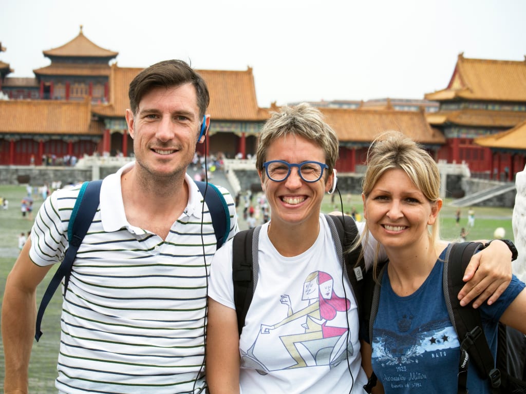 Turisti che posano sorridenti all’ingresso della Città Proibita a Pechino, Cina.