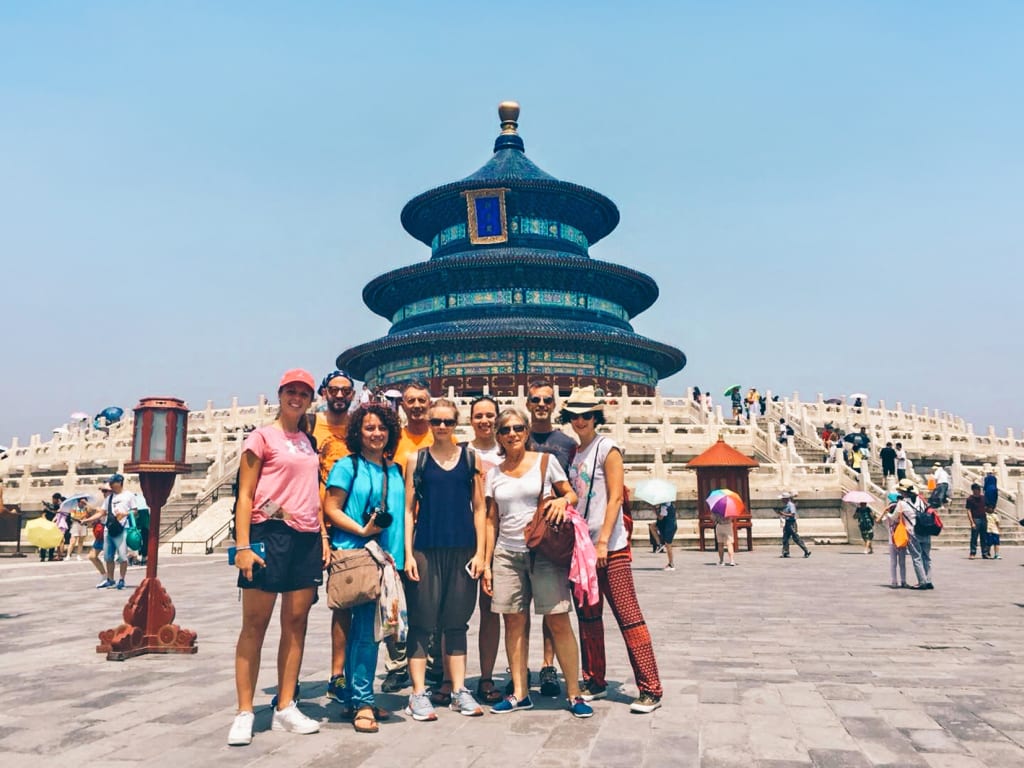 Gruppo di viaggiatori davanti al Tempio del Cielo a Pechino durante una giornata soleggiata.