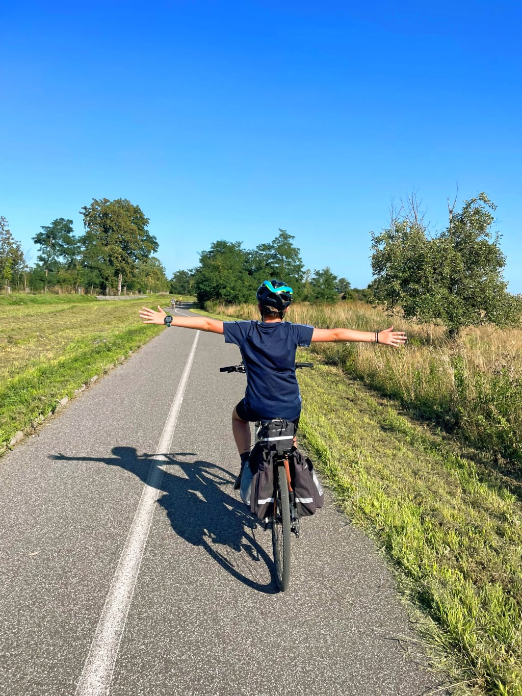Bambino in bicicletta su strada di campagna, viaggio in famiglia lungo itinerari ciclabili sicuri