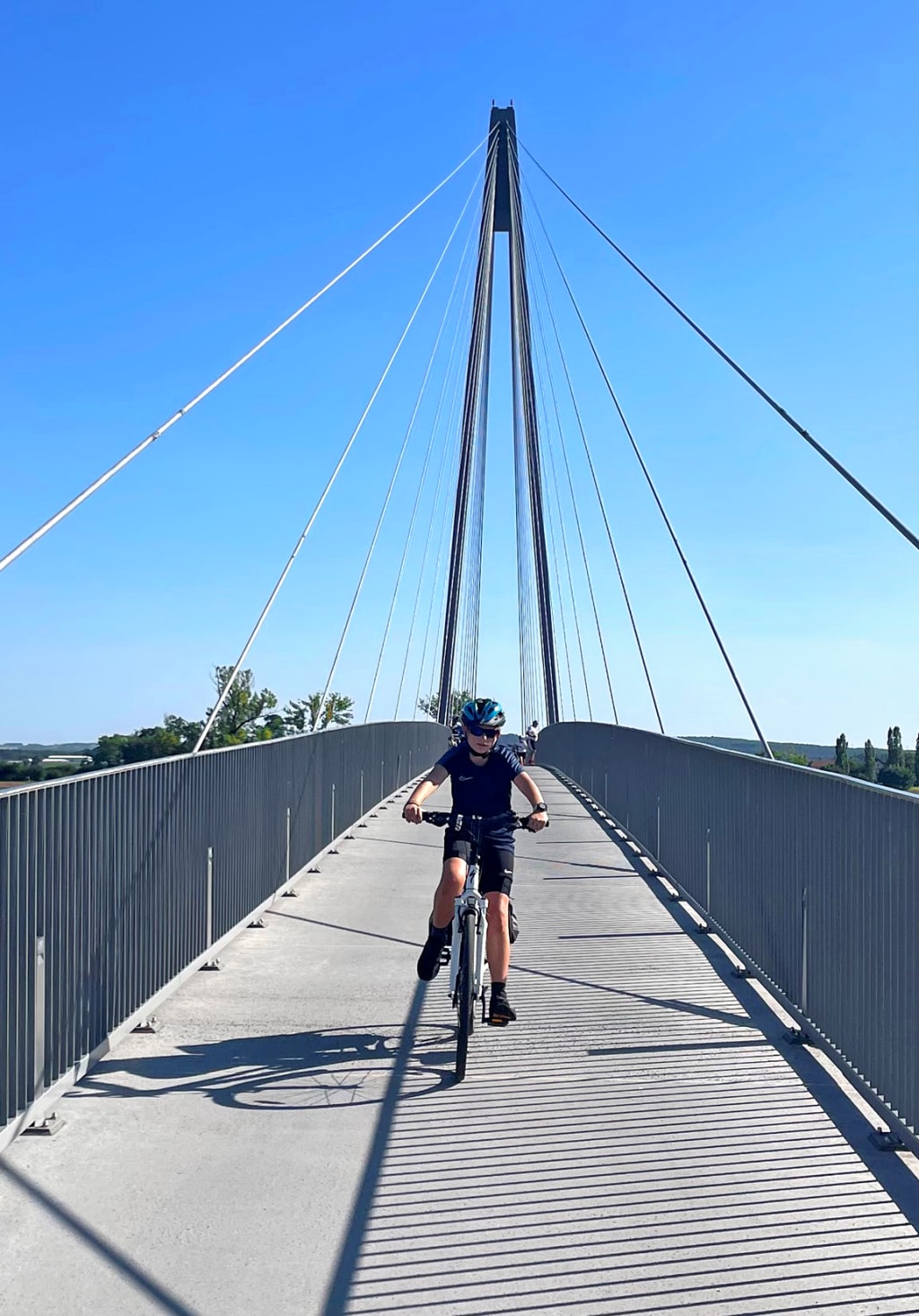Ciclisti che attraversano un ponte moderno sospeso, infrastruttura ciclabile
