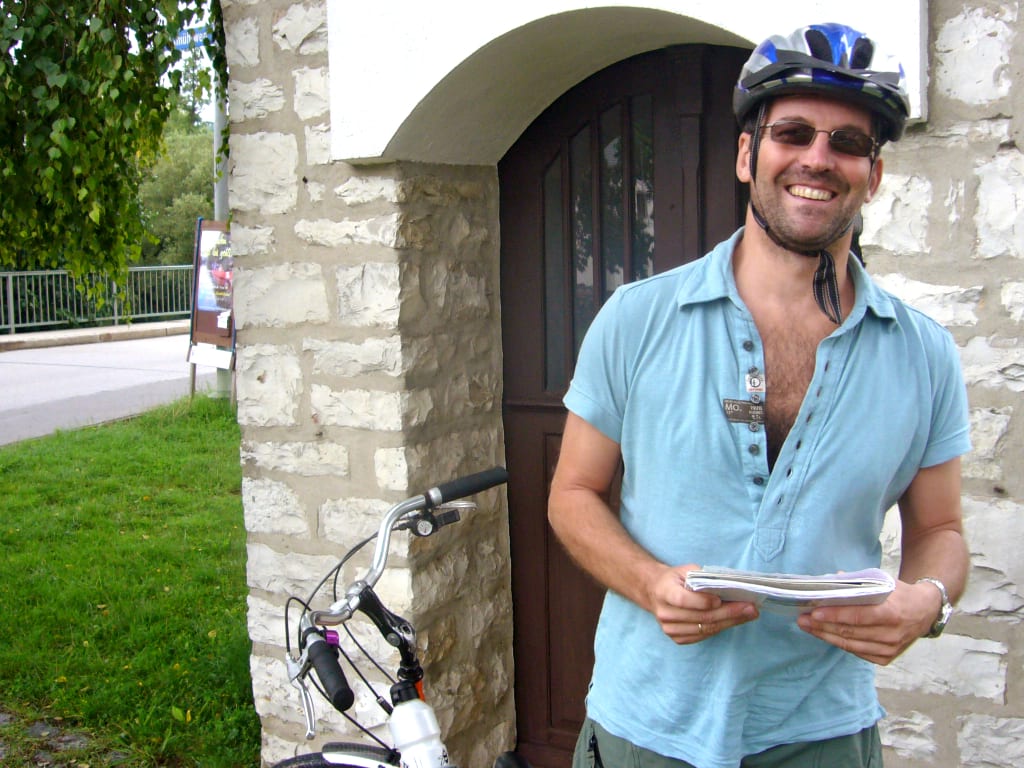 Cicloturista davanti all’ingresso di una cantina vinicola lungo la Route des Vins d’Alsace in Alsazia