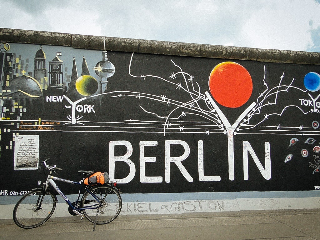 Bici davanti a un murale con la scritta "Berlin" in primo piano su uno sfondo urbano, Berlino.