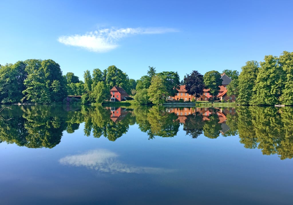 Lago tranquillo con riflessi di alberi e una casa, isola di Fyn, Danimarca