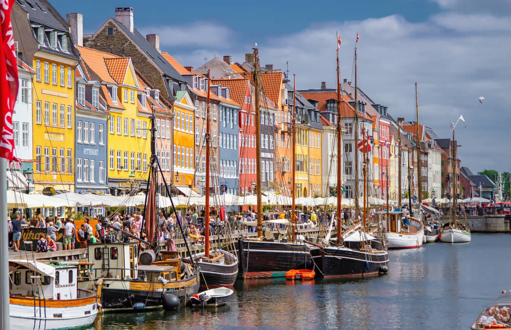 Porto colorato di Nyhavn a Copenaghen, con barche ormeggiate e ristoranti.