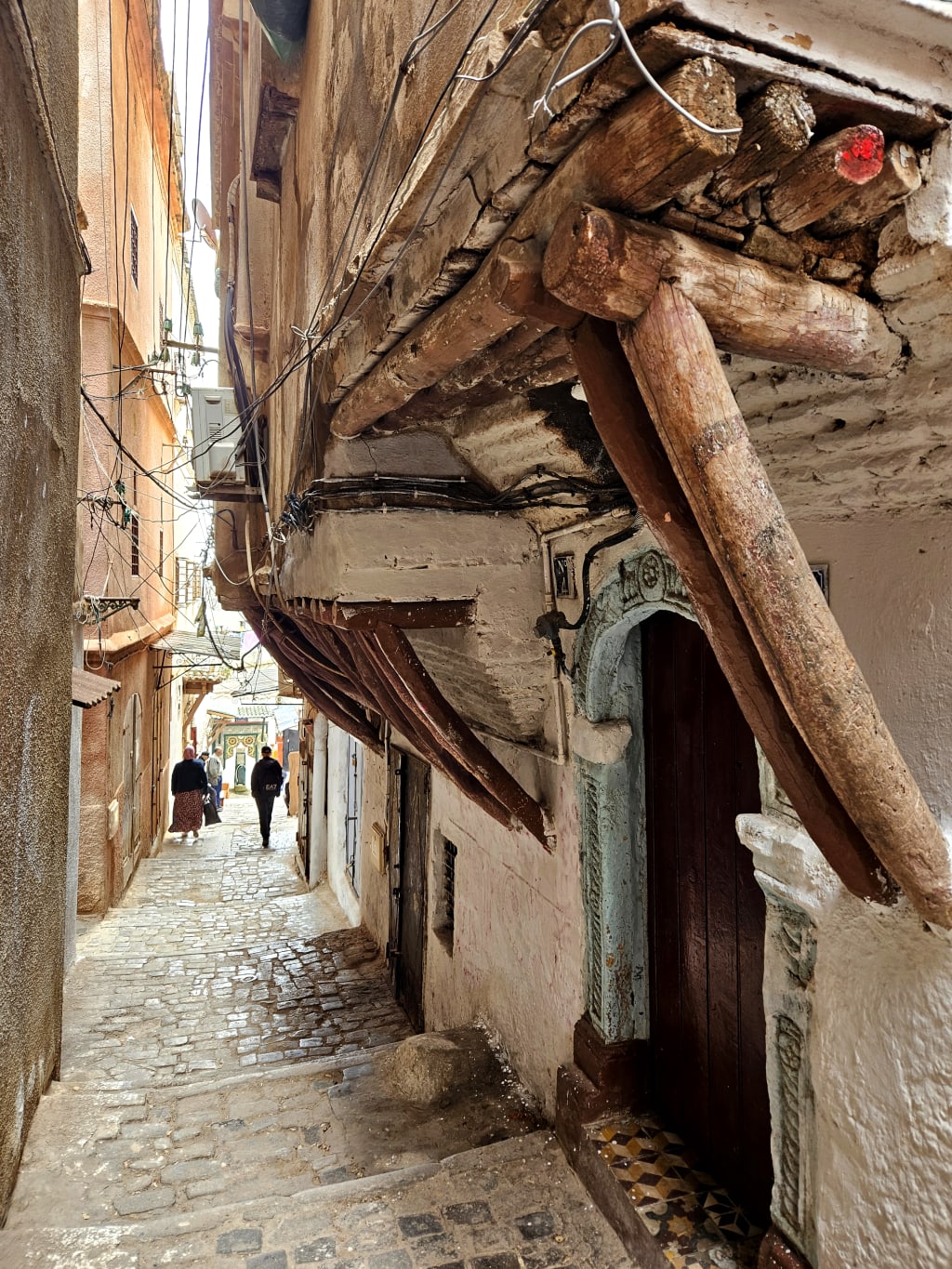 Vicolo stretto della Casbah di Algeri con case tradizionali e travi in legno.