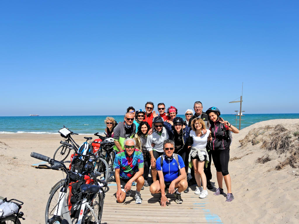Gruppo di cicloturisti sulla spiaggia di Valencia con biciclette, viaggio organizzato nella Comunità Valenciana