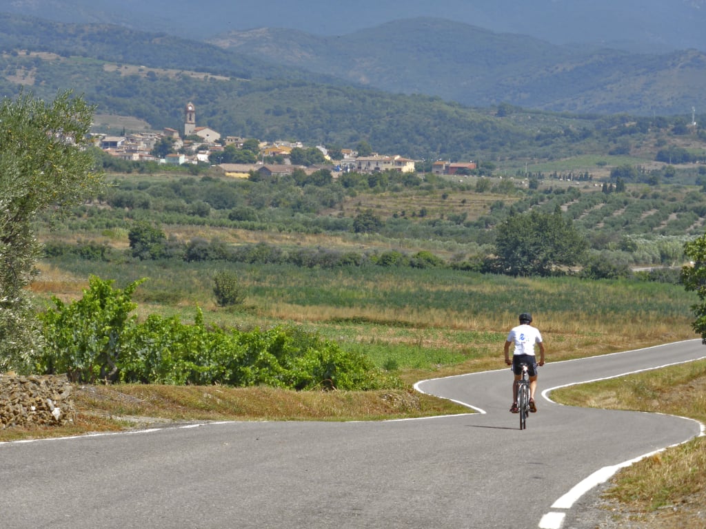 Ciclista che percorre una strada panoramica tra le colline della Catalogna, Spagna, viaggi in bici "Girolibero"