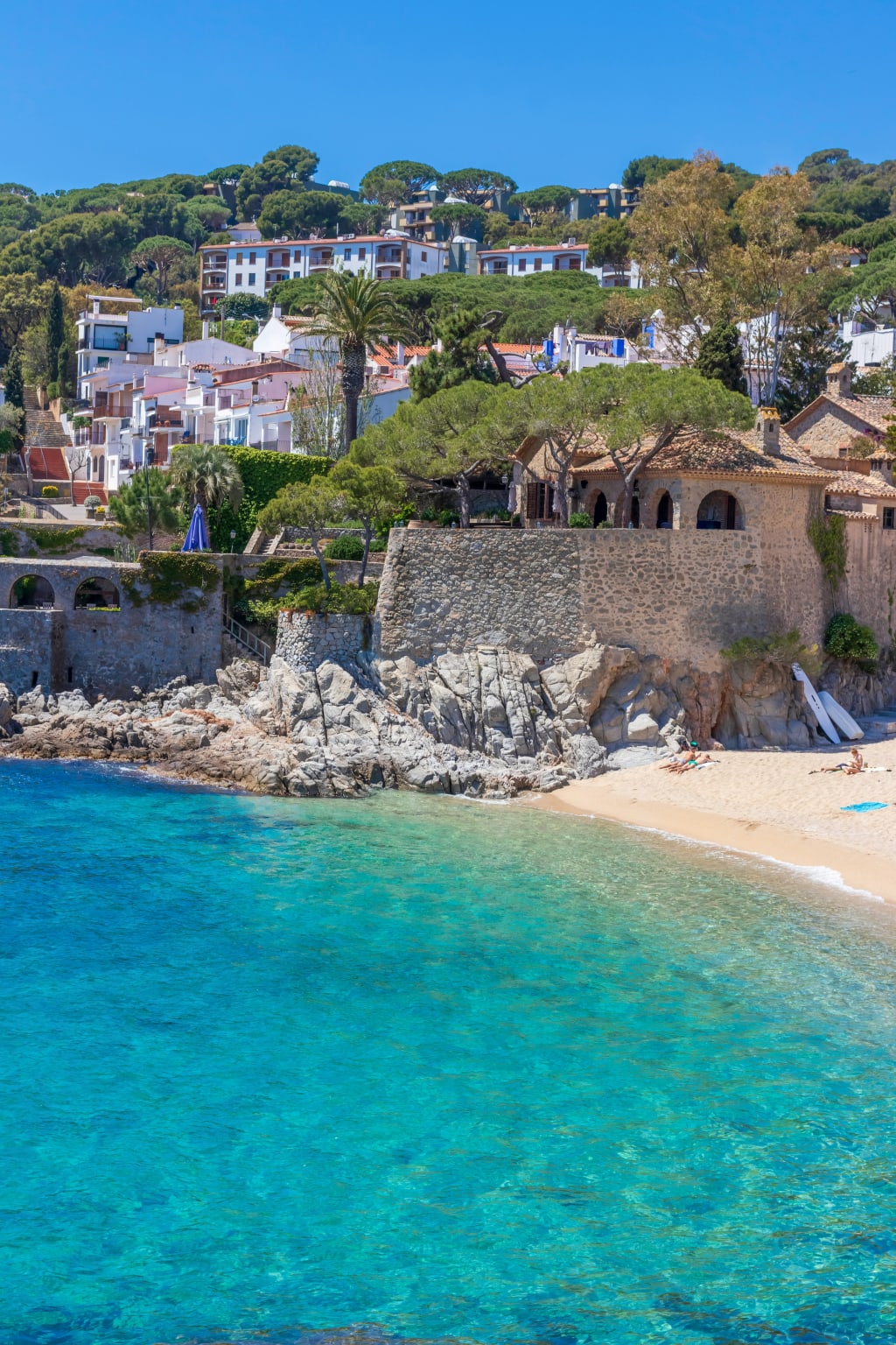 Spiaggia con acque cristalline a Begur, Costa Brava, Spagna, circondata da case e natura.