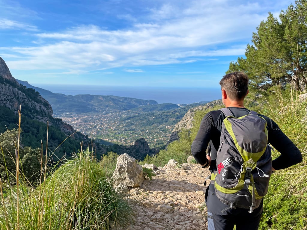 Escursionista su sentiero con vista panoramica con campagna e colline all'orizzonte, trekking a Maiorca
