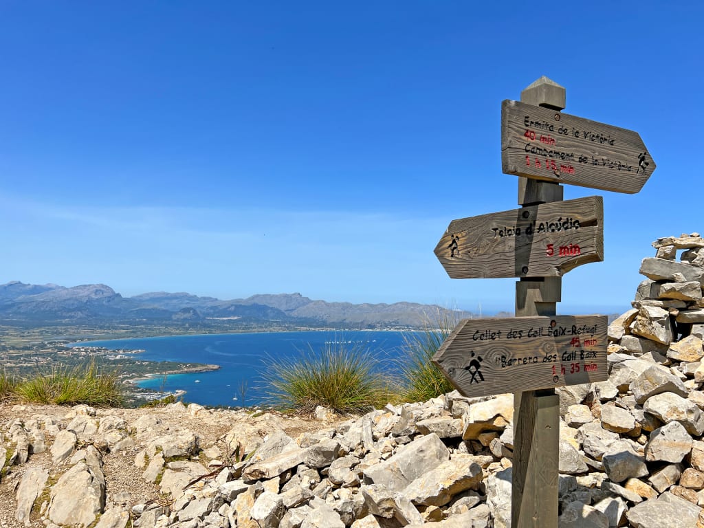 Cartello escursionistico su un sentiero di montagna a Maiorca, Spagna, indicante le direzioni per i percorsi.