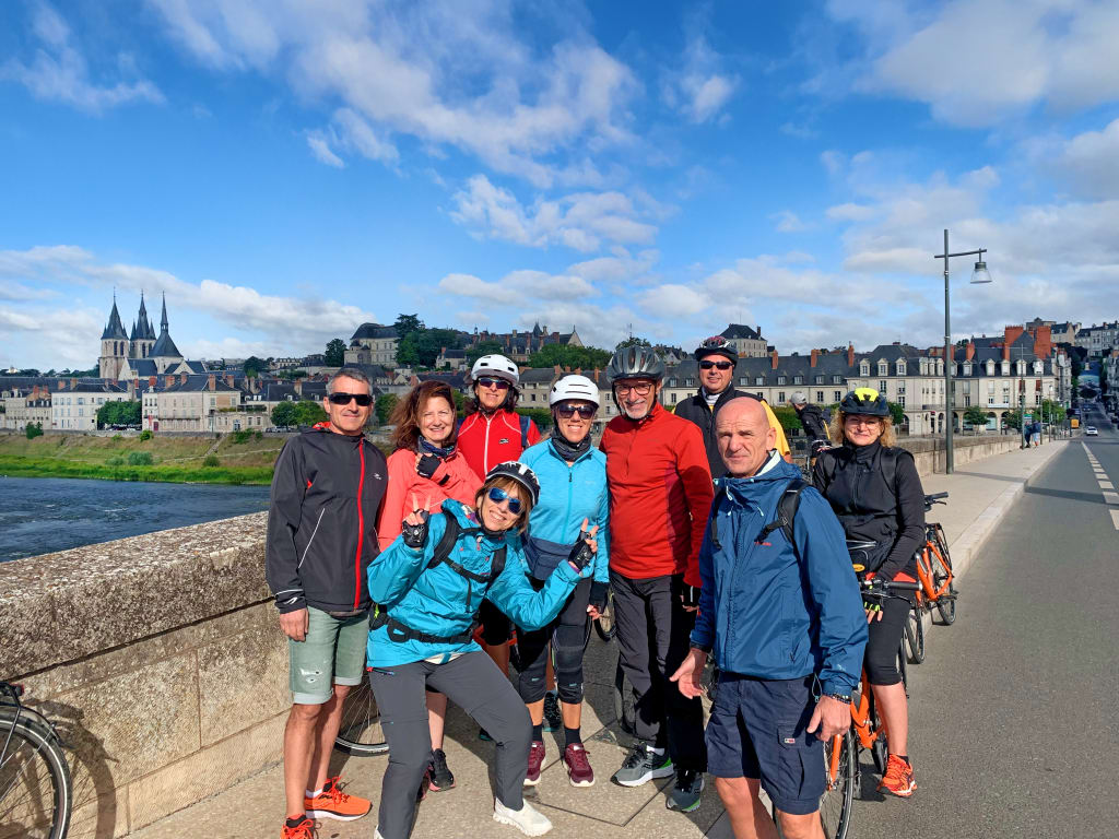Gruppo di visitatori su un ponte sulla Loira con castello sullo sfondo, vacanze in bici "Girolibero"