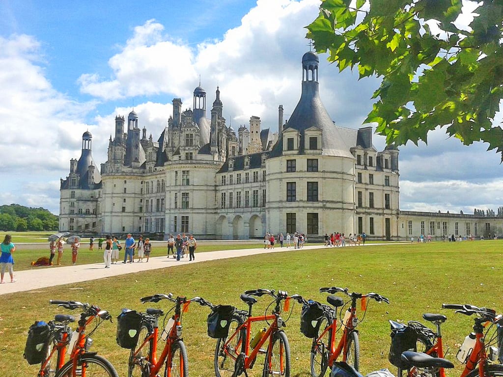 Fila di biciclette Girolibero davanti a Château de Chambord col suo grande prato verde, Castelli della Loira, vacanze in bicicletta