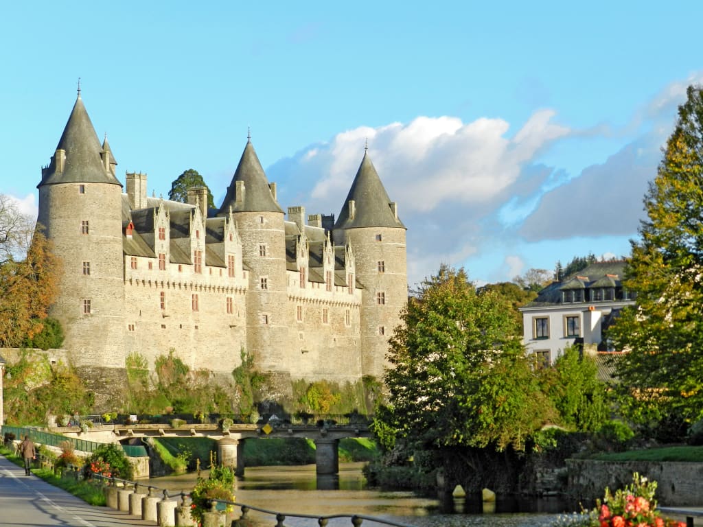 Veduta di un castello storico francese lungo un fiume, tipico della Bretagna, tappa scenografica per itinerari culturali e cicloturistici.