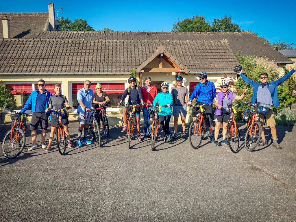 Gruppo di cicloturisti in Bretagna davanti a tipica casa in pietra, viaggio organizzato in bici lungo la costa atlantica