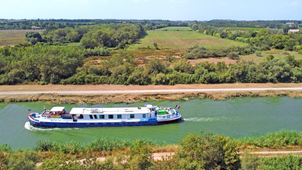 Imbarcazione "Girolibero" sul fiume con percorso ciclabile lungo la riva, Provenza e Camargue, Francia