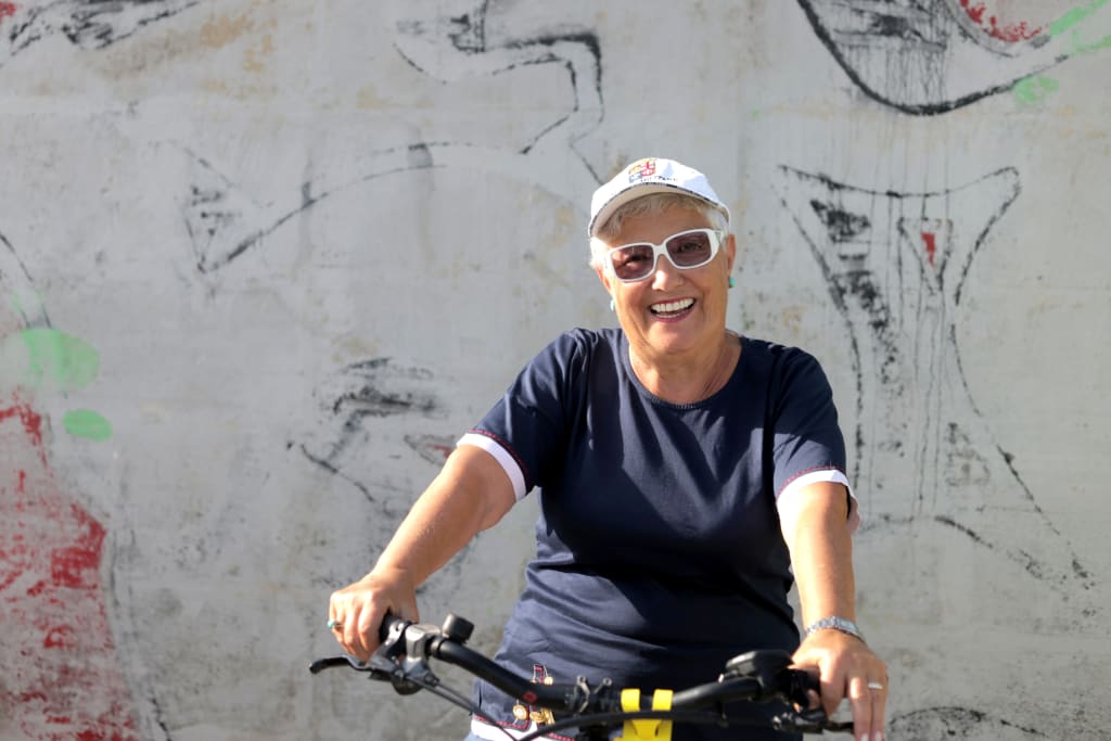 Donna sorridente in sella a una bici elettrica "Girolibero", vacanze in barca e bicicletta