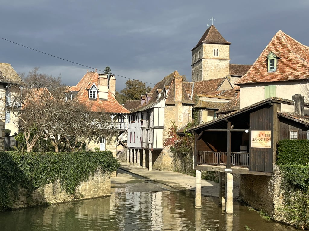 Borgo medievale sul fiume con case in pietra nel sud della Francia, paesaggio storico attraversato durante un viaggio slow