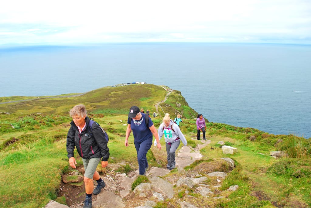 Gruppo di persone che cammina su un promontorio verde con vista sull'oceano in Irlanda del Nord.