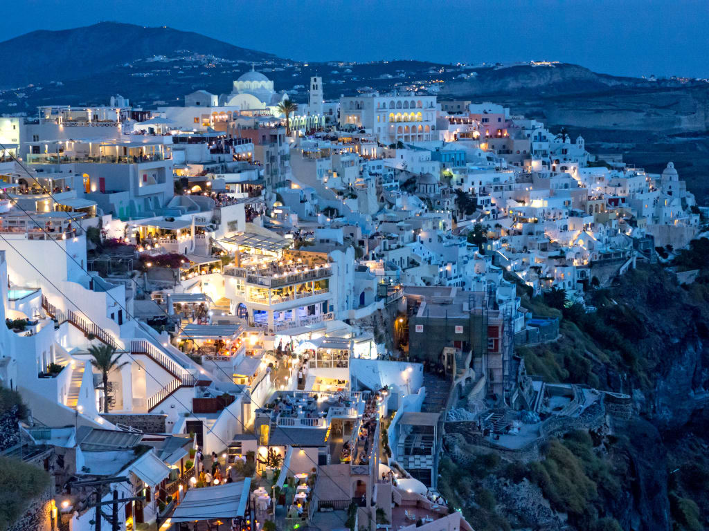Vista panoramica su Oia al tramonto, con case bianche e il mare sullo sfondo, Santorini, Grecia.