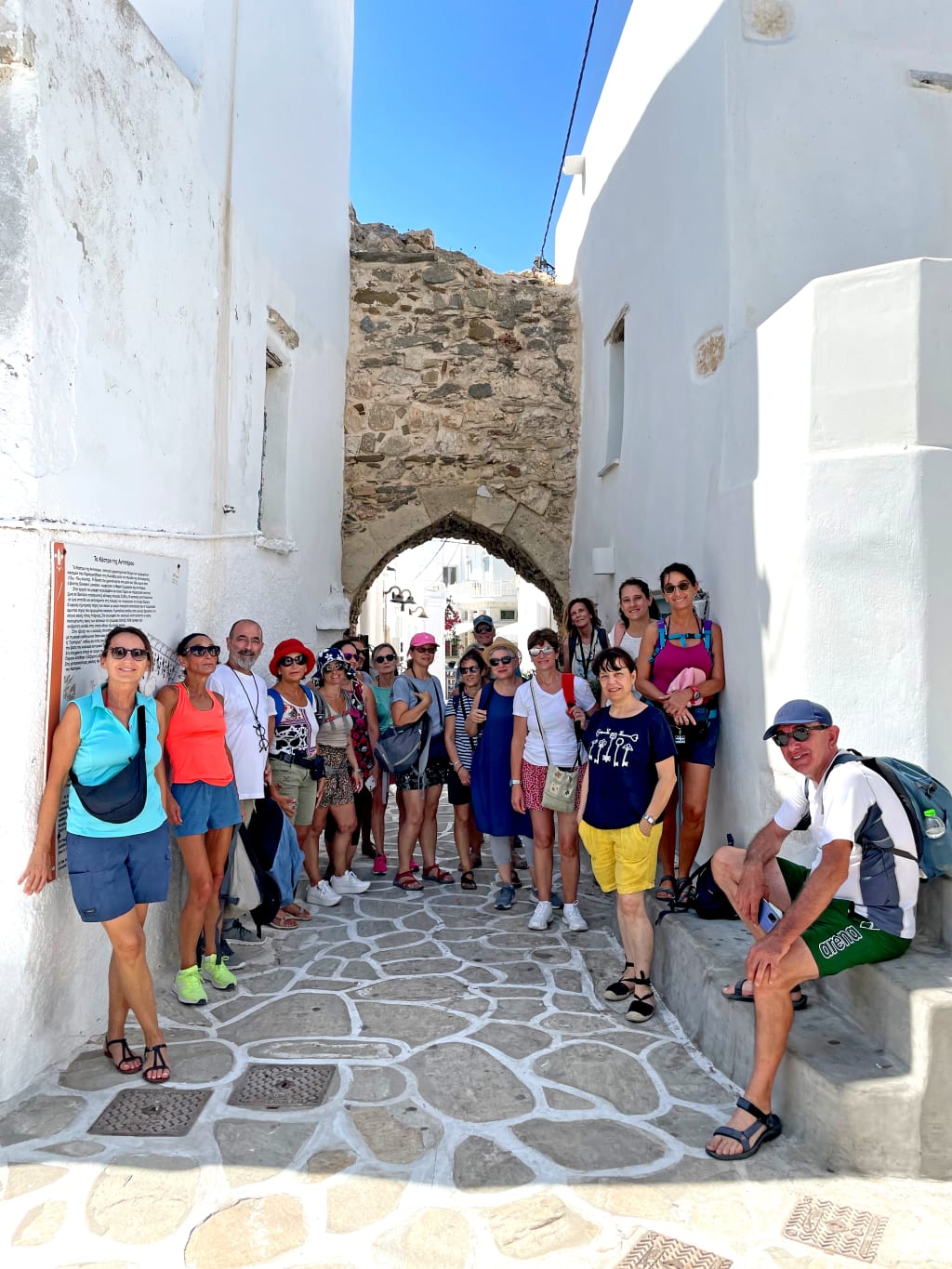 Turisti in viaggio con Girolibero lungo una via nell'antico villaggio di Oia, Santorini, Grecia.