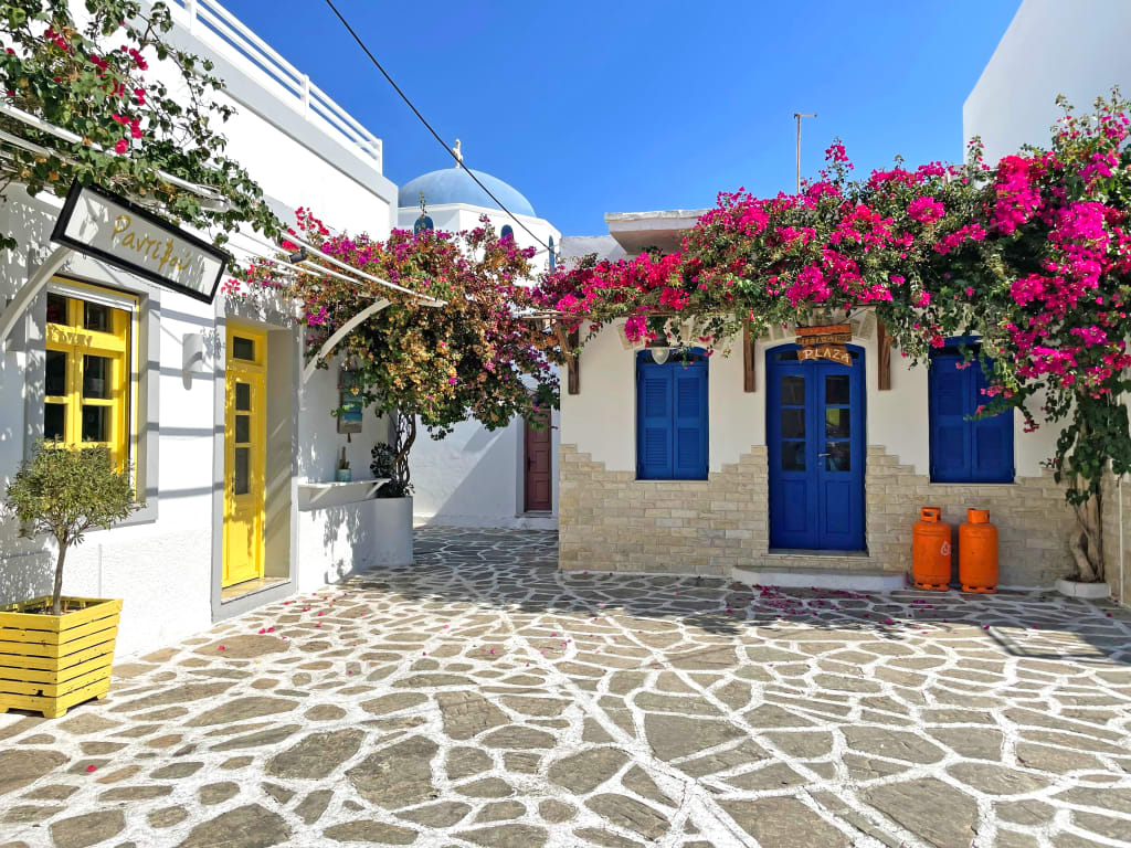Strada lastricata con case bianche e finestre blu nel centro di Mykonos, Grecia.