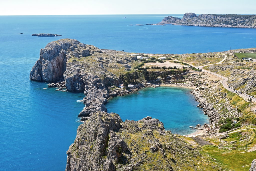 Vista aerea della Baia di San Paolo e del villaggio di Lindos, con mare turchese e paesaggio costiero, Rodi, Grecia.