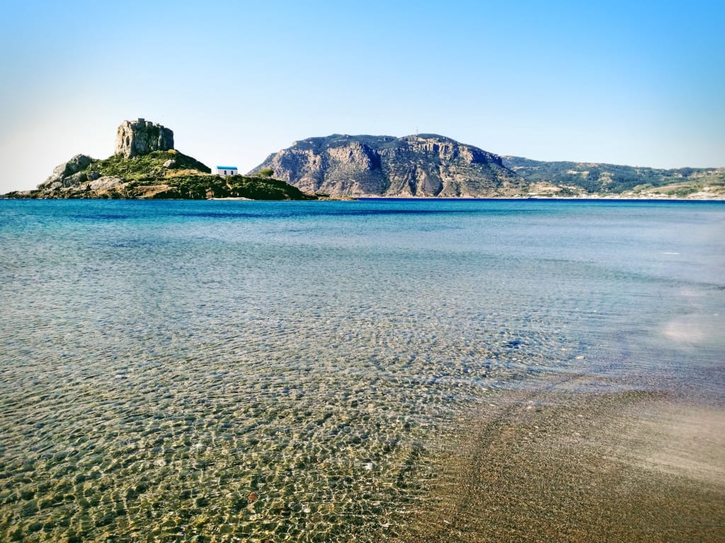 Spiaggia a Kos con mare trasparente e fondale sabbioso.