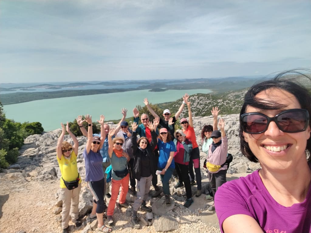 Gruppo di viaggiatori sorridenti in posa panoramica, esperienza di viaggio di gruppo durante una vacanza attiva in Europa.