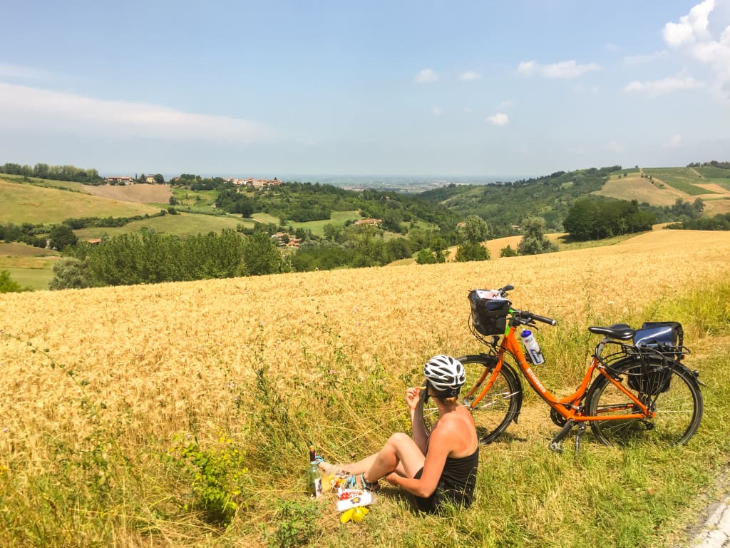 Turista in bicicletta si rilassa in un campo dorato nelle campagne del Monferrato.