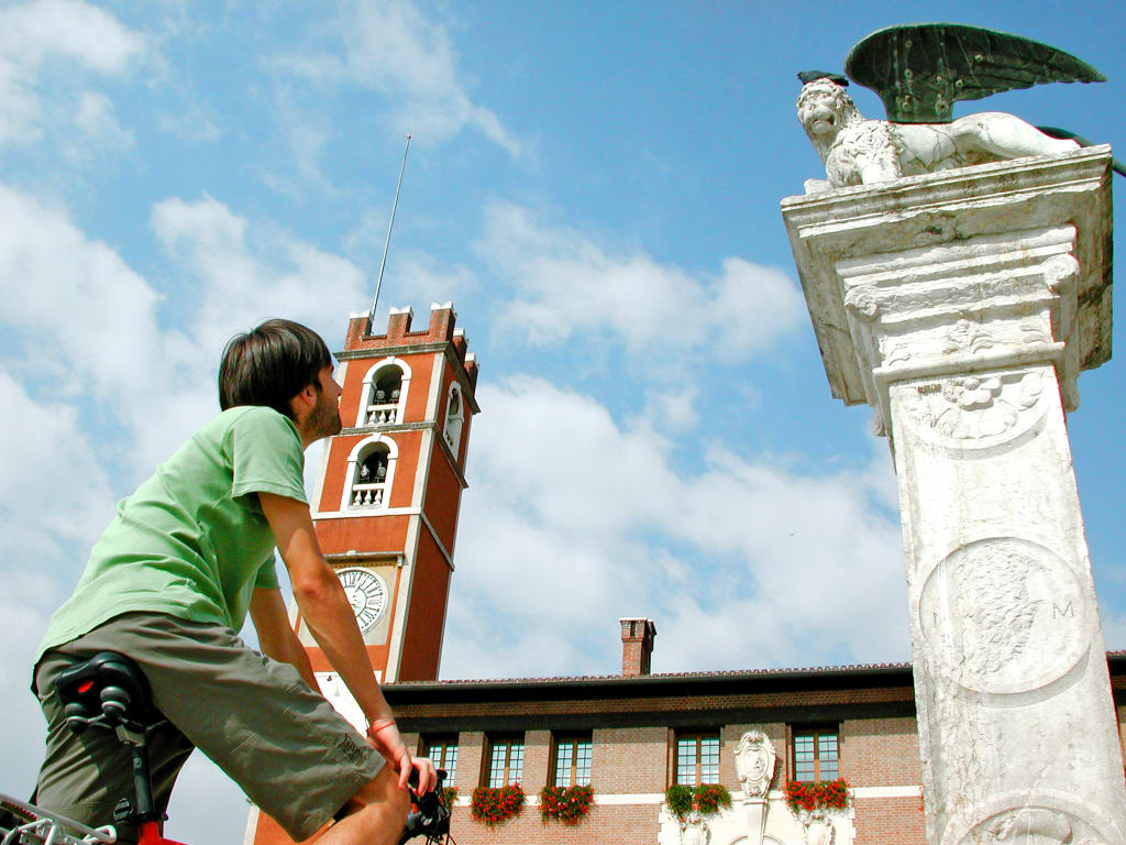 Ciclista in viaggio con "Girolibero" osserva il campanile in Piazza degli Scacchi a Marostica