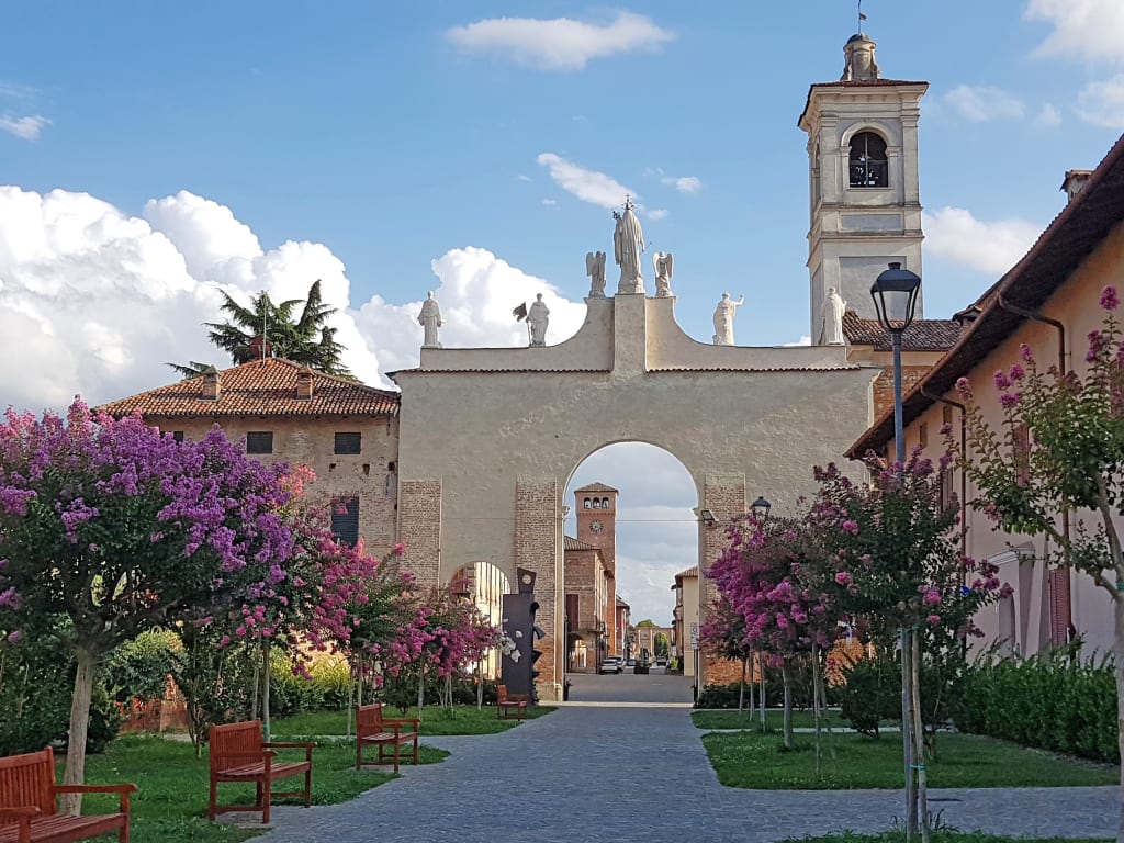 Facciata dell'Arco del Belvedere di Cherasco con aiuole fiorite.