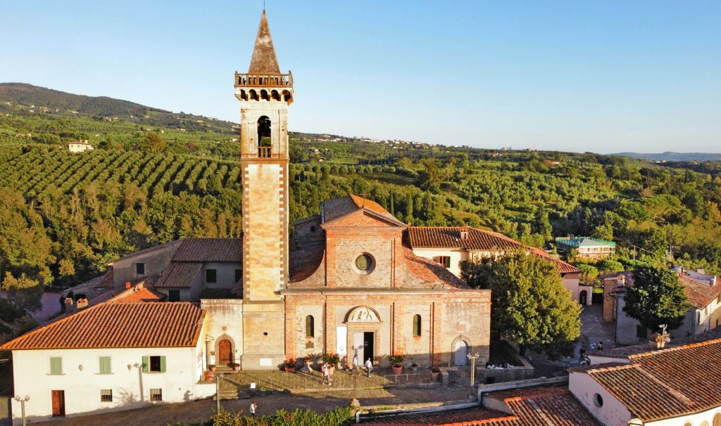 La chiesa di Santa Croce a Vinci, circondata da colline e vigneti tipici del paesaggio toscano, Italia.
