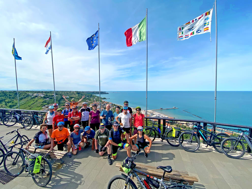 Ciclisti che posano vicino alle bandiere a Campo Imperatore, Abruzzo, Italia