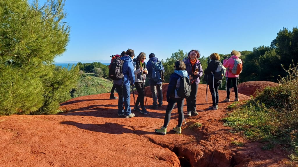 Gruppo di escursionisti su sentiero rosso nella natura, trekking di gruppo in ambiente mediterraneo.