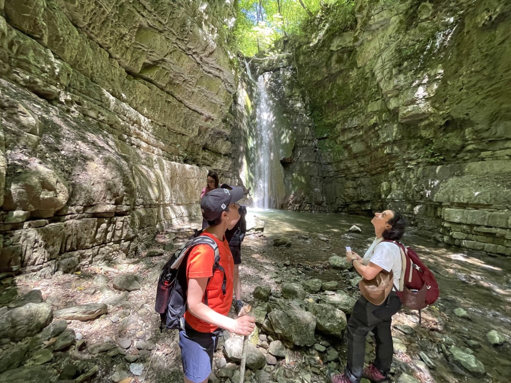 Escursionisti all’interno di una gola verde della Basilicata con pareti rocciose, trekking avventura nella natura