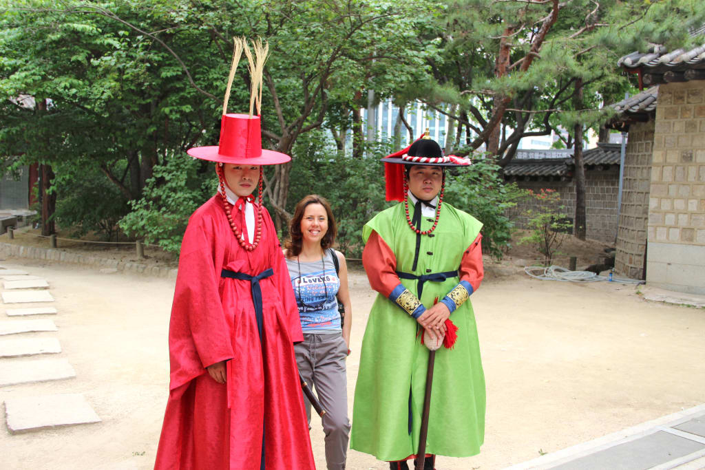 Persone in abiti tradizionali coreani hanbok davanti a un tempio.