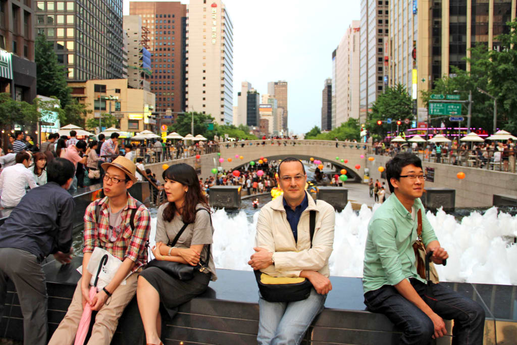 Turisti in vacanza in gruppo con Girolibero seduti su una fontana nella città di Seoul, Corea del Sud.