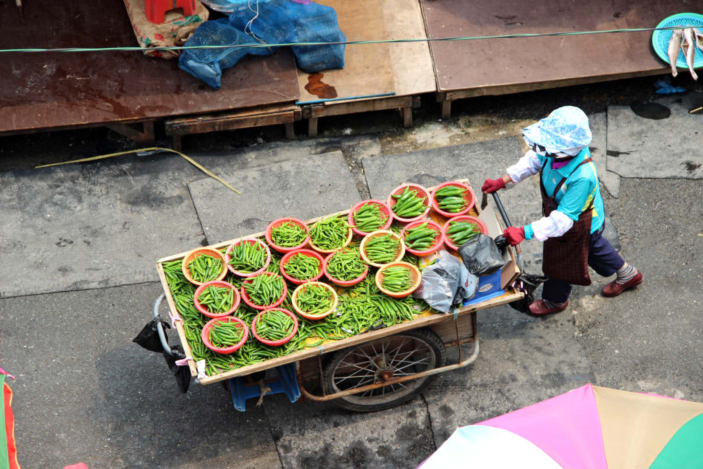 Venditrice ambulante coreana con un carretto di frutta e verdura.