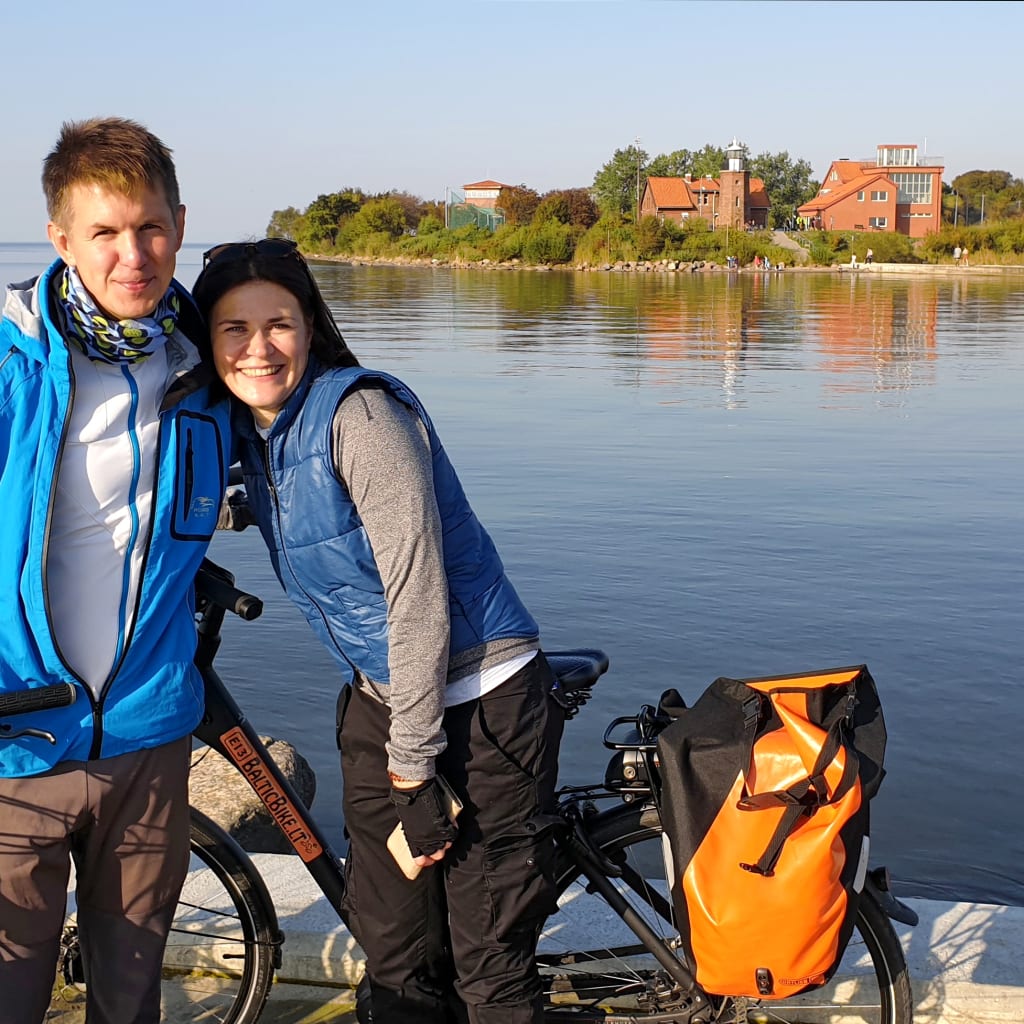 Coppia di cicloturisti vicino alla laguna di Neringa, Penisola dei Curi, con paesaggio panoramico.