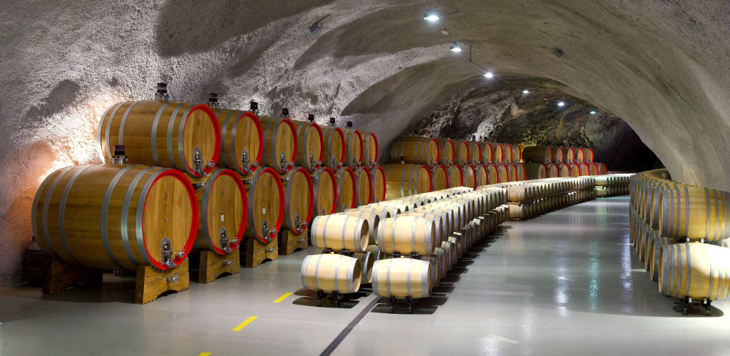 Cantina con botti di vino in un tunnel sotterraneo.